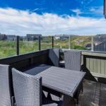 Terrasse mit Sitzgruppe und Blick auf grüne Hügel und Häuser.