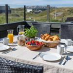 Frühstückstablett auf Terrasse mit Blick auf Hügel und Häuser.