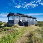 Moderne Strandhaus mit großem Fensterfront und grüner Umgebung.