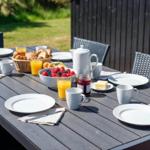 Gedeckter Essbereich im Freien mit Tisch, Stühlen und Frühstück.