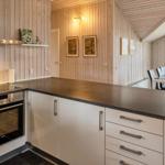 Küche mit Essbereich, Holzwand und Glasfront zum Garten.
