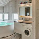 Bad mit Whirlpool, Dusche und Waschmaschine. Holzwände und Fenster.