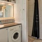 Badezimmer mit Waschmaschine, Spiegel und Duschvorhang.