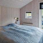 Schlafzimmer mit Bett, Holzwand und Terrassentür.