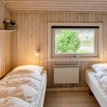 Zwei Einzelbetten in einem Holzraum mit Fenster und Heizung.