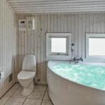 Bad mit Whirlpool, Toilette und Dusche. Holzwände und Fenster.