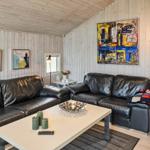 Wohnzimmer mit zwei schwarzen Ledersofas, Tisch und Wandbildern.