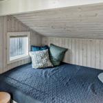 Schlafzimmer mit Bett, Fenster und Holzwandverkleidung