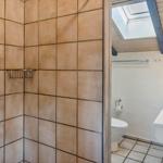 Badezimmer mit Dusche, Toilette und Waschbecken unter Dach