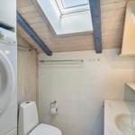 Badezimmer mit Waschmaschine, Toilette und Waschbecken unter Dachschrägen.