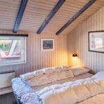Schlafzimmer mit Bett, Fenster und Holzwandverkleidung.