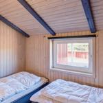 Zwei Betten in einem Holzraum mit Fenster und Deckenbalken.