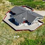 Haus mit Terrasse und Grillplatz auf grüner Wiese.