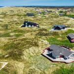 Dorf auf Dünen mit Häusern und Strand im Hintergrund.