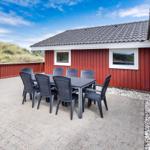Roter Holzaussenbereich mit Tisch und Stühlen. Hintergrund: Dünen und blauer Himmel.
