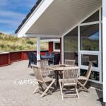 Terrasse mit Tisch und Stühlen neben einem Haus mit Glasfront.
