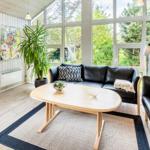 Wohnzimmer mit schwarzen Sofas, Holztisch und großem Fenster zur Aussicht.
