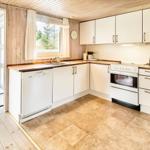 Küche mit weißen Schränken, Steinboden und Blick in Wohnzimmer