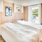 Zwei Betten, Holzwände, Fenster und Stühle im Schlafzimmer.