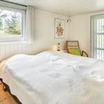 Schlafzimmer mit Bett, Fenster und Glastür zum Balkon.