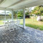 Terrasse mit Tisch und Stühlen, Blick auf Garten und Baum.