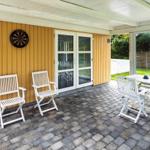 Terrasse mit weißem Tisch und Stühlen, gelbem Holzhaus und Dartscheibe.