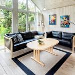Wohnzimmer mit schwarzen Sofas, braunem Sessel und großem Fenster.