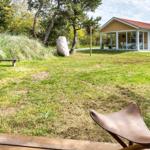 Vorgarten mit Gras, Stein und Bank. Im Hintergrund Haus mit Terrasse.