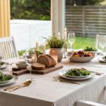 Gedeckter Tisch mit Salat, Brot und Kerzen im Freien.