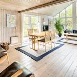 Wohnbereich mit Kamin, Esstisch und Sofa. Große Fenster, Holzboden und Möbel.