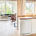 Küche mit Waschmaschine und Blick in Wohnzimmer mit Sofa und Tisch.