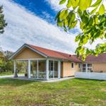 Ein Haus mit Terrasse und Garten unter Bäumen. 