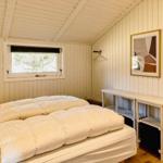 Schlafzimmer mit Bett, Fenster und Kleiderständer an der Wand.