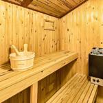Sauna mit Holzbank, Eimer und Heizung.