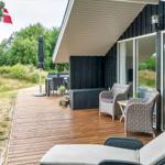 Terrasse mit Liegestühlen, Tisch und Stühlen. Daneben Flagge und Grünflächen.