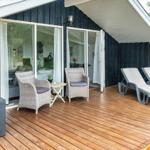 Terrasse mit Liegen und Sitzgelegenheiten vor einem Haus mit Schiebetüren.