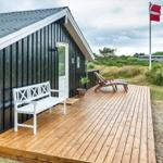 Hütte mit Holzterrasse, weißem Stuhl und Liegestühlen. Daneben weht die dänische Flagge.