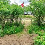 Weg durch grüne Vegetation zu einem Haus mit dänischer Flagge.