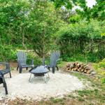 Außenbereich mit vier Sitzgelegenheiten und Grillplatz im Wald.