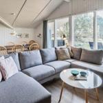 Ein Wohnzimmer mit grauem Sofa, runden Tisch und großen Fenstern.