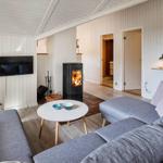 Wohnzimmer mit grauem Sofa, Kamin und Fernseher an der Wand.