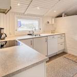 Küche mit Arbeitsplatte, Spüle und Waschmaschine. Fenster und Holzboden.