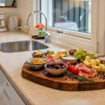 Küche mit Holzbrett, Käse, Wurst, Trauben und Gewürzen auf Arbeitsfläche