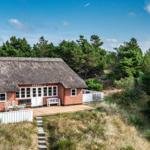 Rotes Holzhaus mit Strohdach, Terrasse und Garten im Wald.