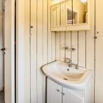 Badezimmer mit Waschbecken, Spiegel und Dusche.