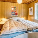 Schlafzimmer mit Holzwand, Bett und Fenster mit Blick auf Grün.