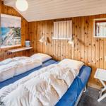Zimmer mit zwei Betten, Holzwänden und Fenster. Tisch mit Blumen und Wandbilder.