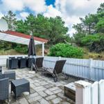 Terrasse mit Sitzgelegenheiten, Sonnenschirm und Blick auf grüne Bäume.