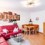 Wohn- und Essbereich mit rotem Sofa, Esstisch und Holzmöbeln.