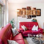 Ein Wohnzimmer mit rotem Ledersofa, Glas-Tisch und Wandbildern.